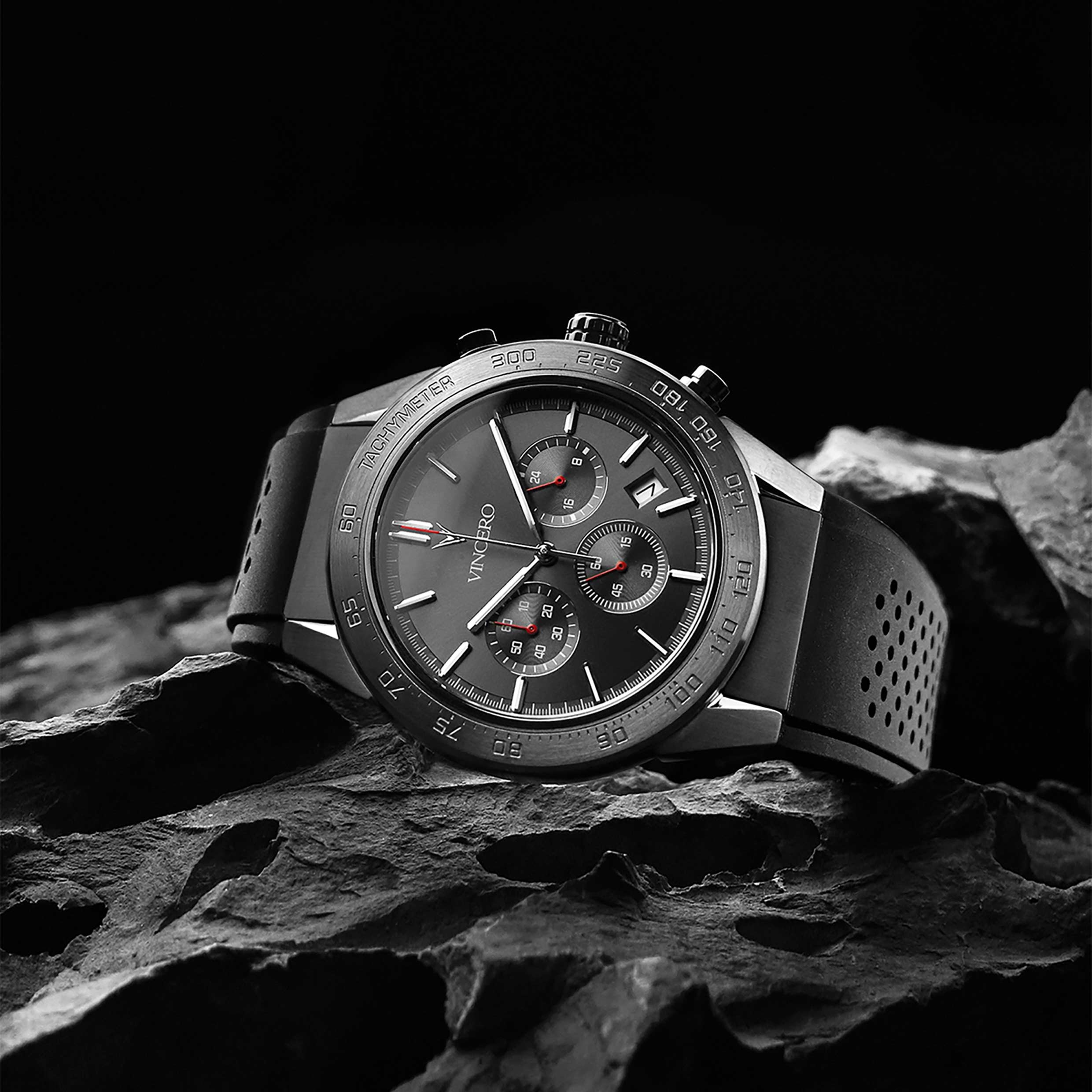 Luxury watch with detailed face and black strap on a dark rock background